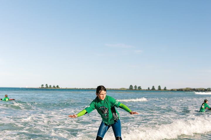 Person in green wetsuit surfing on small waves.