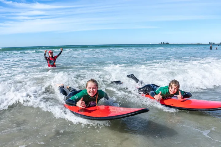 a little girl riding a wave on a surfboard in the water