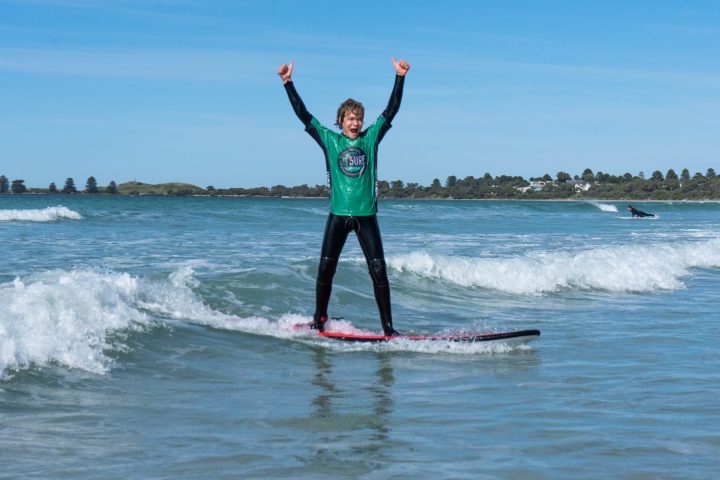 a girl riding a wave on top of a body of water