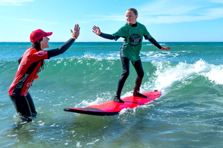 a young girl riding a wave on a surfboard in the ocean