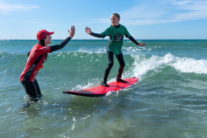 a young girl riding a wave on a surfboard in the water