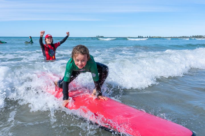 a young girl riding a wave on a surfboard in the water