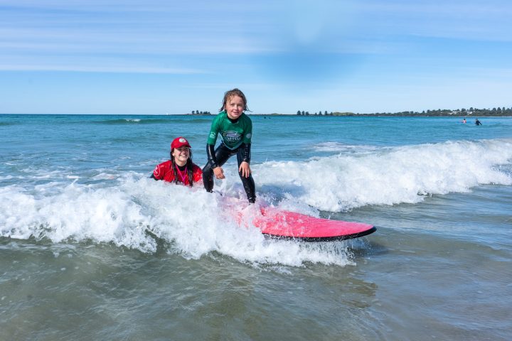 a young girl riding a wave on a surfboard in the ocean