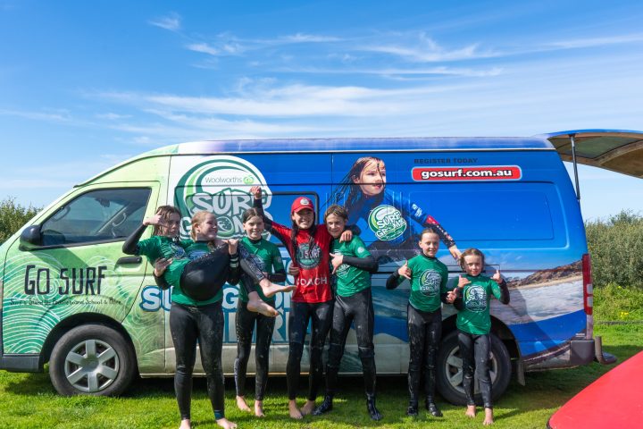 a group of people standing in front of a car posing for the camera