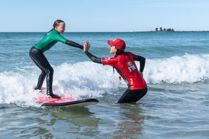 a young girl riding a wave on a surfboard in the water